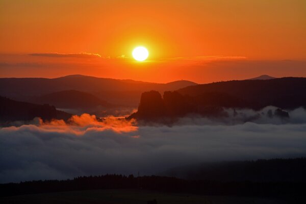 Wolken am Fuße der Berge bei Sonnenuntergang