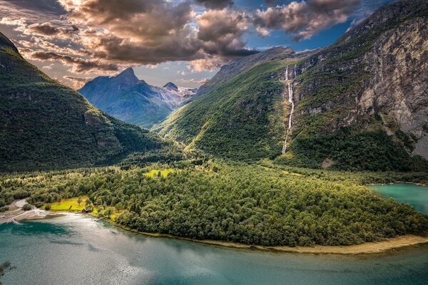 Panorama of green mountains and hills with a forest valley and a water surface