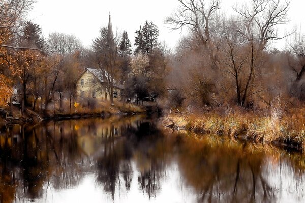 Two-storey house by the lake in the forest in autumn