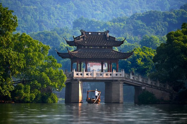 Chinesische Brücke mitten im Fluss auf einem Hintergrund von Bäumen