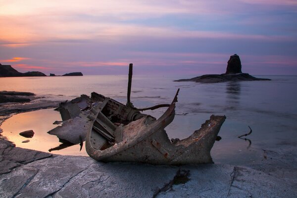 The wrecked ship at the night coast of the sea