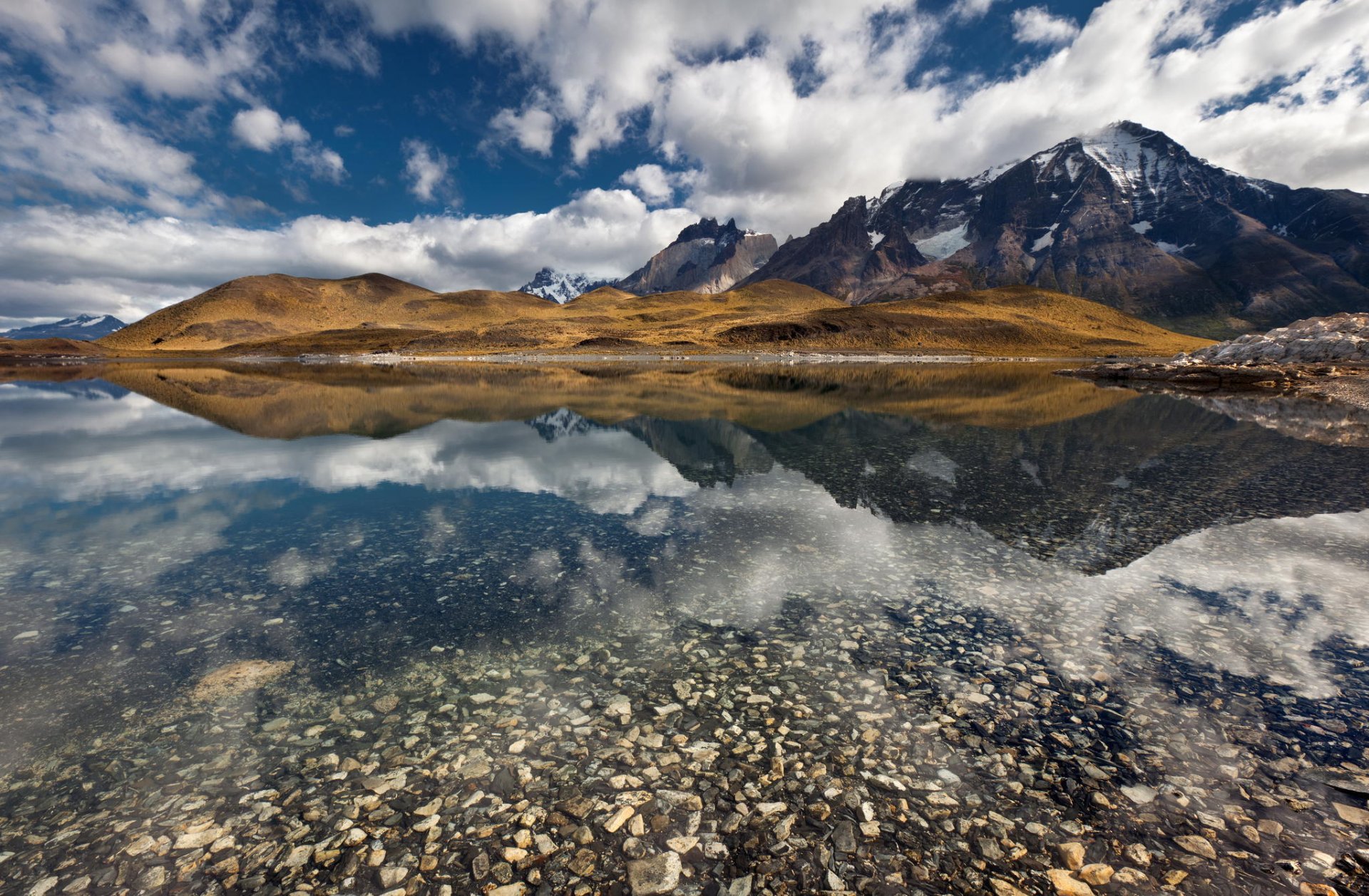 montañas picos nieve lago reflexión fondo piedras orilla