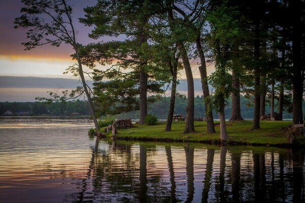 A lake with trees on the shore with a reflection of the sky