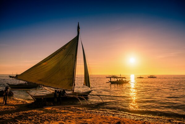 Barca vicino alla riva al tramonto. Tramonto serale tranquillo sul mare nelle Filippine