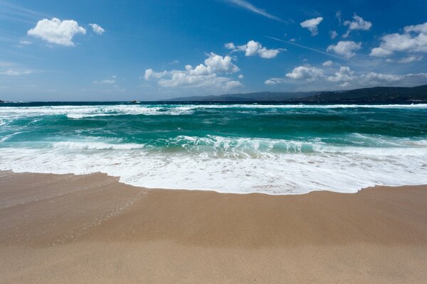 Turquoise waves with foam storms on the sand