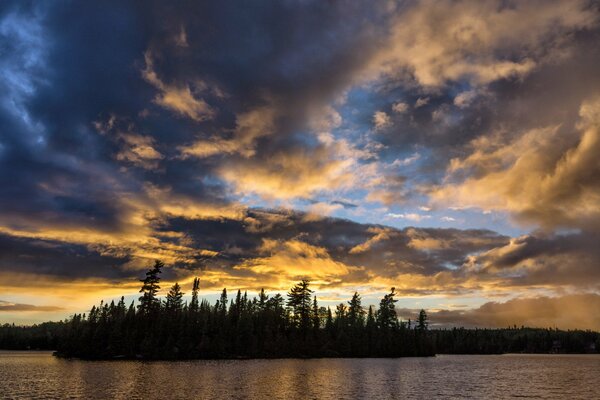 La orilla del lago en el fondo de la puesta de sol de oro