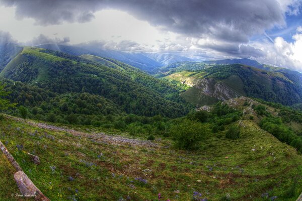 Eine Wiese mit Hügeln, über denen Wolken schweben