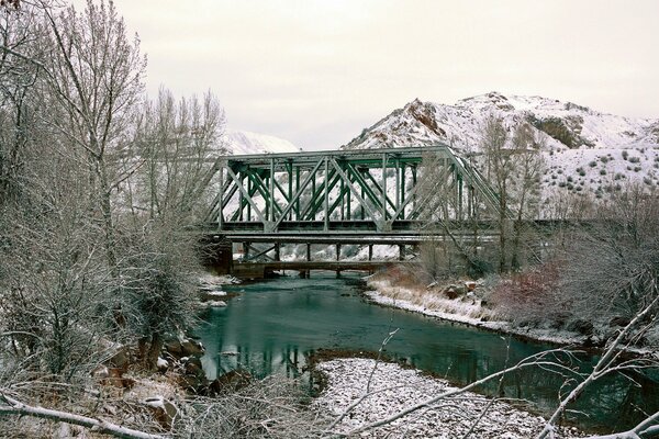 Imagen de invierno de un puente sobre un fondo de montañas y árboles