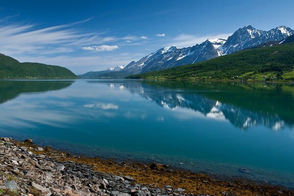 Il cielo blu e le montagne si riflettono nel lago