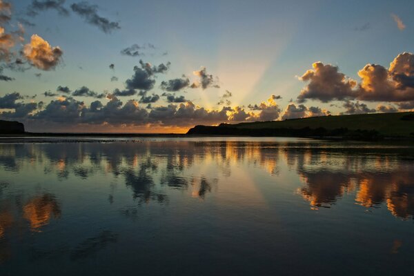 Sonnenaufgang am Fluss mit der Reflexion der Wolken im Wasser