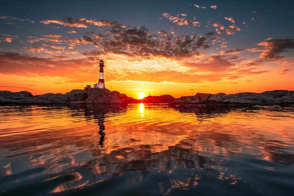 Puesta de sol naranja sobre el mar y el faro