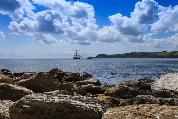 A sailboat at sea. View from the rocky shore