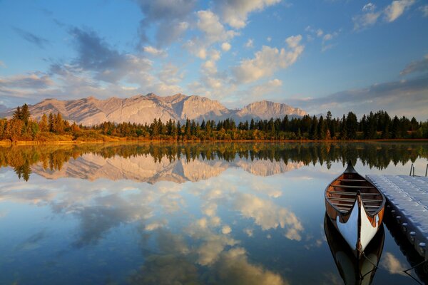 Boat at the pier in the lake against the background of the forest and the state with a cloudy sky