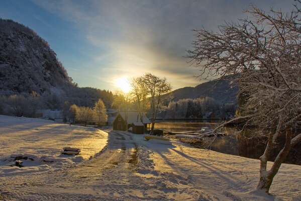 Coucher de soleil et montagnes. Route enneigée à la maison près de la rivière