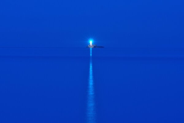 Mar azul en la noche. Faro en la isla