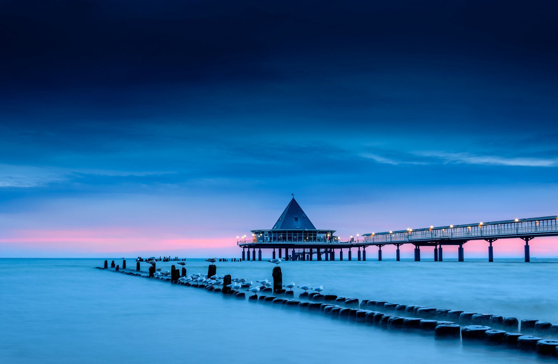 ea shore pillars pier bridge lanterns lighting birds seagulls blue blue pink sky clouds morning