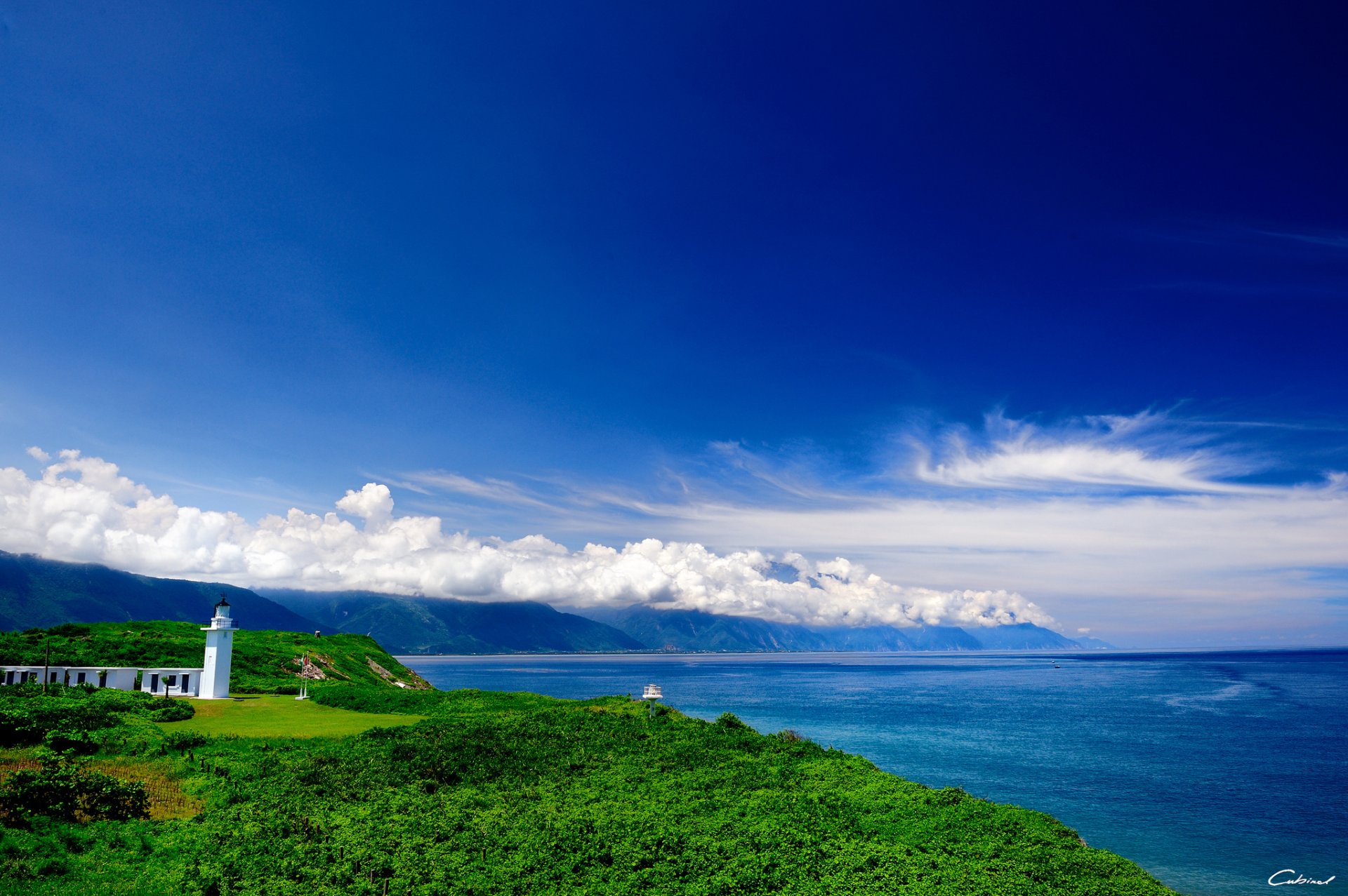 mer verdure phare bâtiments collines nuages côte