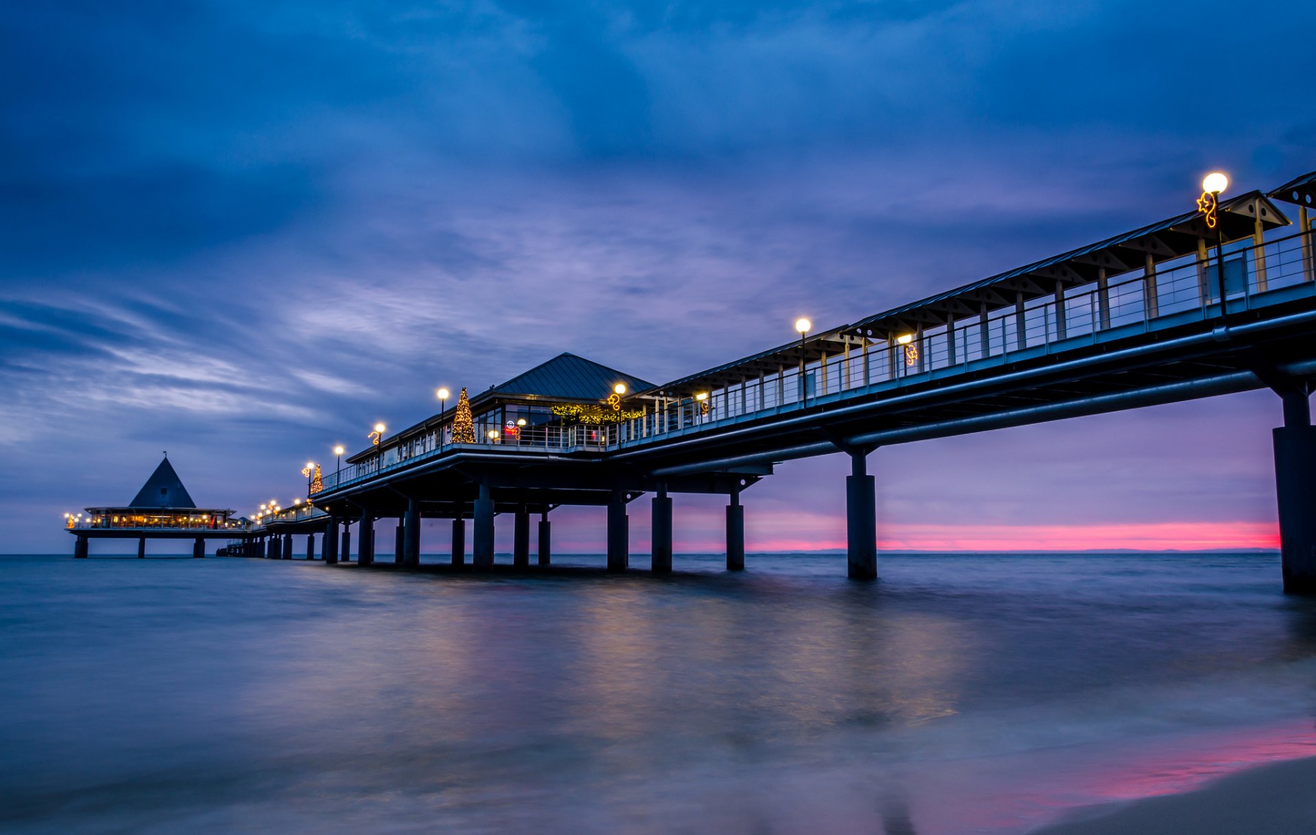 meer küste pier brücke abend blau flieder himmel wolken purpurrot sonnenuntergang beleuchtung lichter licht laternen weihnachtsbaum urlaub