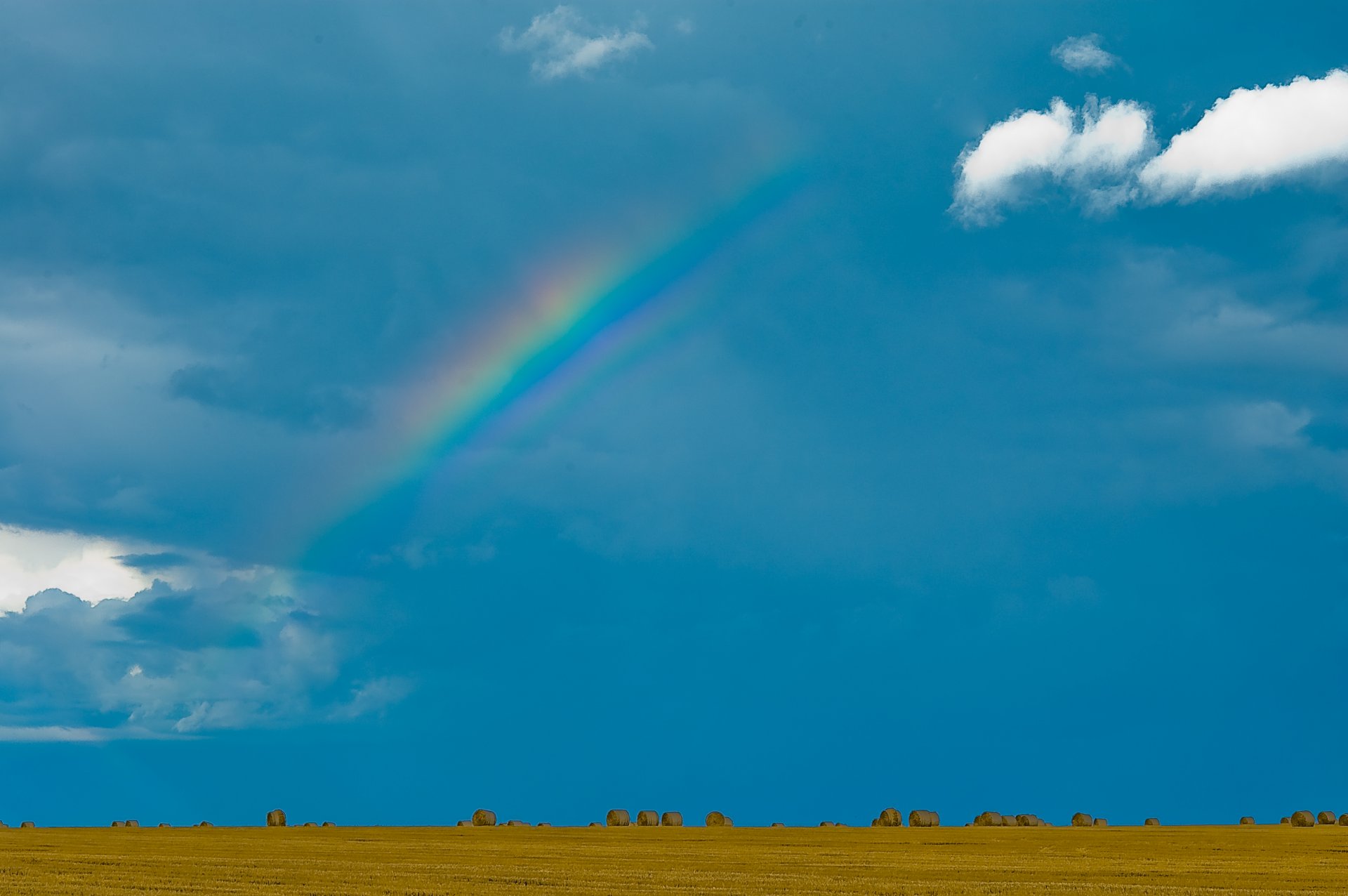 campo balle fieno pressato cielo arcobaleno nuvole