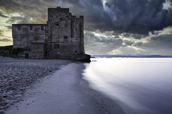 Torre sombría en la orilla del mar al atardecer