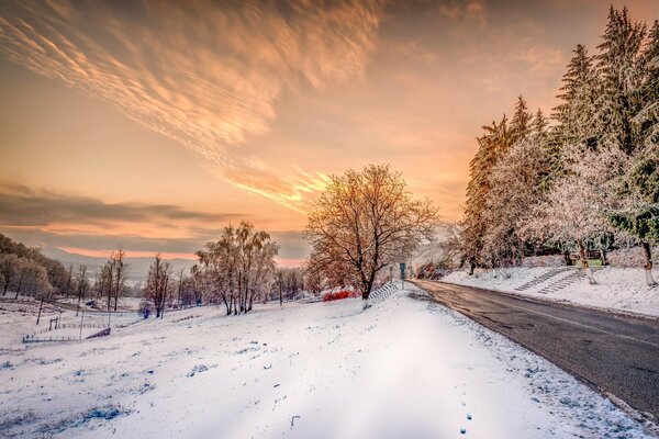 Winter landscape with snowy road and sunset