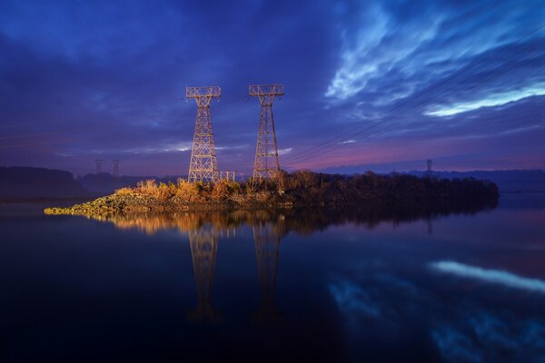 Lines of power lines in the reflection of water, against the dark blue evening sky