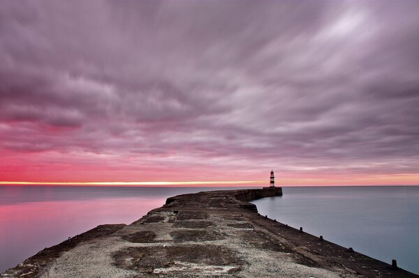 Dawn at sea. Pier and lighthouse