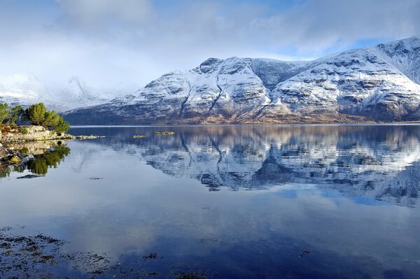 Evening mountains in the snow are reflected in the lake