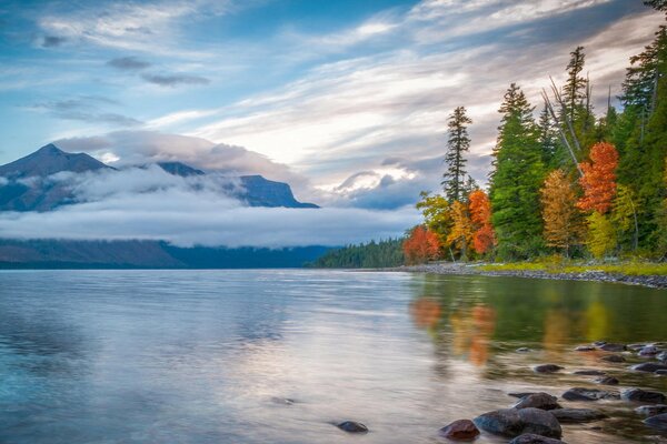 Berge in Wolken und Wald spiegeln sich im See wider