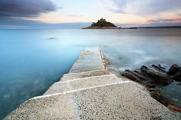 A stone road leading to the blue sea and a beautiful sunset