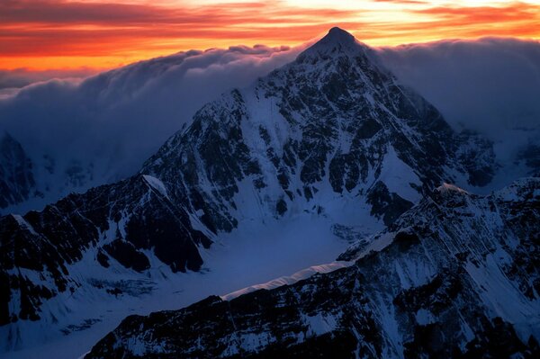 Sonnenaufgang auf dem Gipfel eines Berges mit schneeweißen Wolken