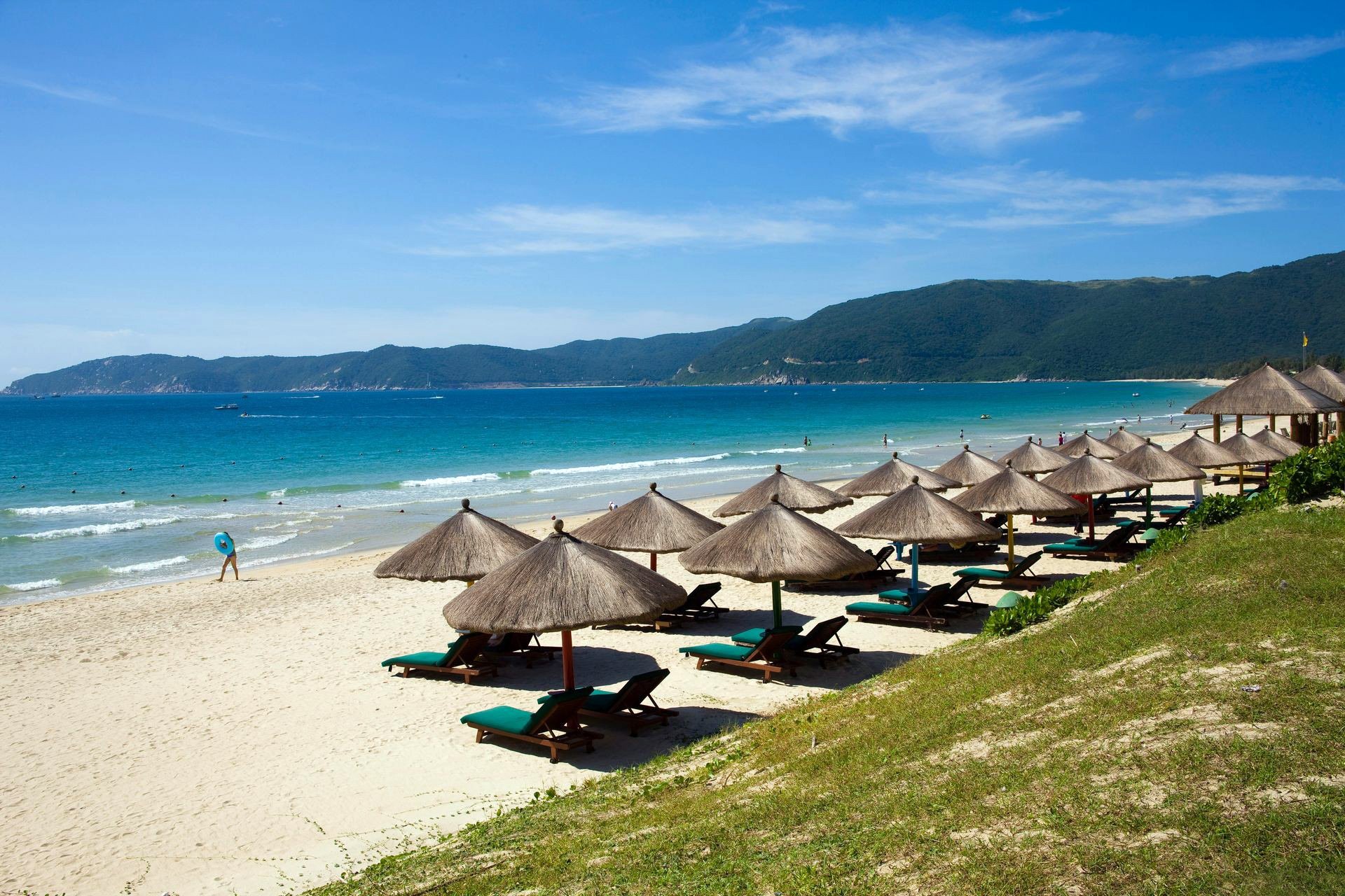 mare oceano costa spiaggia sabbia ombrelloni paglia dal cielo montagna resort relax sedie a sdraio surf