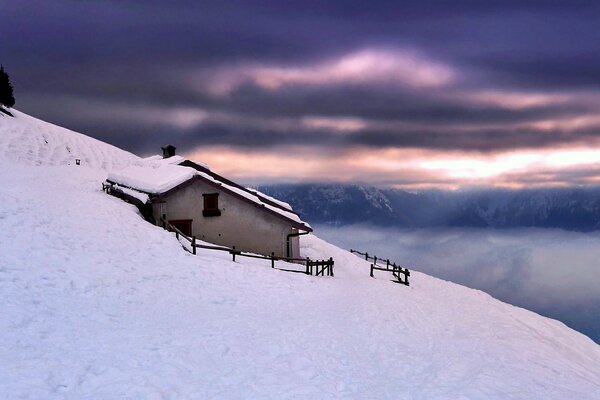 Eine einsame Hütte in einer Schneewehe am Berghang