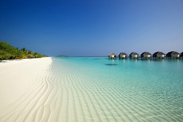 Weißer Sandstrand mit blauem Meer und Bungalows