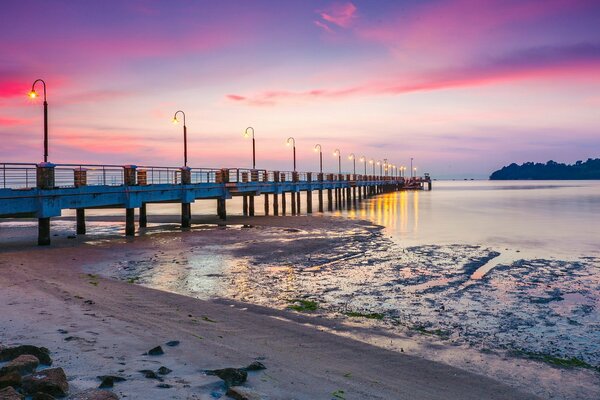 Puesta de sol en el puente en el mar