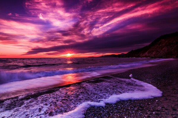 Coucher de soleil lilas et vague avec de la mousse sur la plage