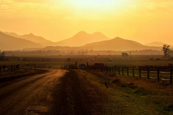 A road with a beautiful landscape leads through the fence