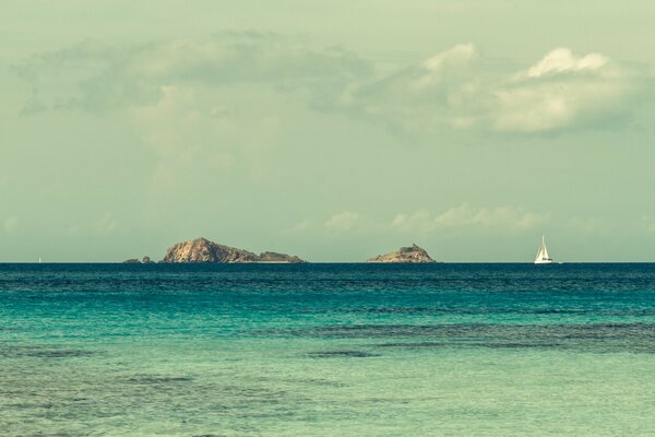 White sailing yacht in the ocean near the islands