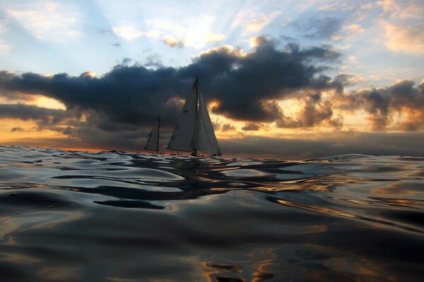 The sea at sunset and sailboats in the distance