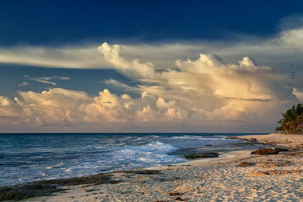 The exciting sea at the sandy beach and thick clouds in the sky