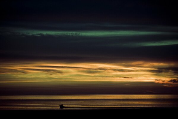 The clouds have thickened in the sea, but the boat is visible at sunset