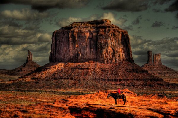 Vaquero a caballo durante la puesta de sol en el desierto