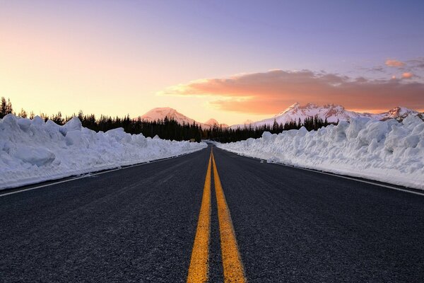 Strada con segni gialli e cumuli di neve sul ciglio della strada