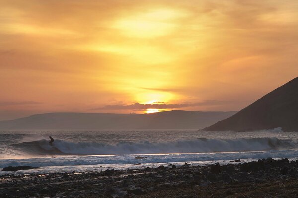 Sonnenuntergang am Strand mit Wellen