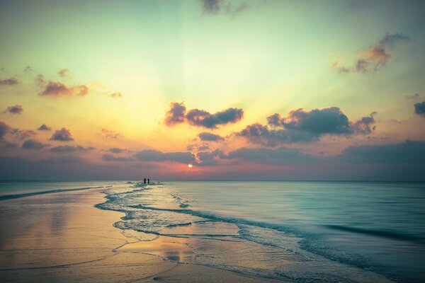 Beau coucher de soleil écarlate sur fond de couple marchant sur la plage