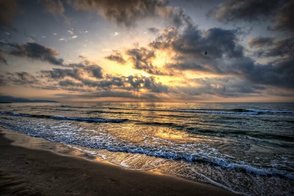 Sea with waves and sand during sunset