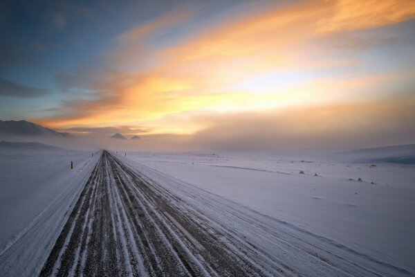 Winter road to nowhere with a beautiful sunset sky