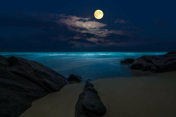 Full moons at the rocks at night at the beach