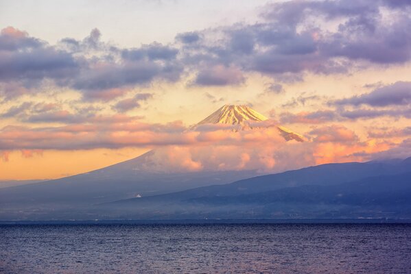 Volcán que llega a las nubes en la orilla del lago