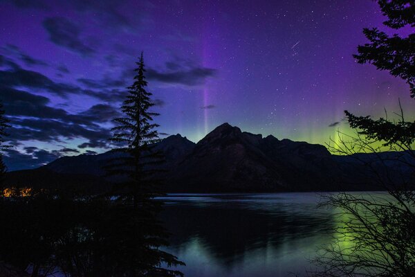 Aurores boréales dans la nuit sur fond de montagnes et de lacs